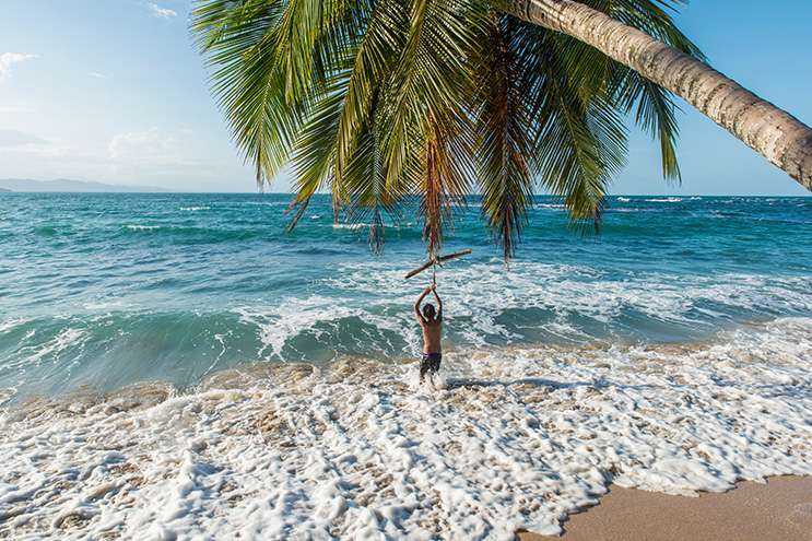 Kind unter einer Palme im Meer.